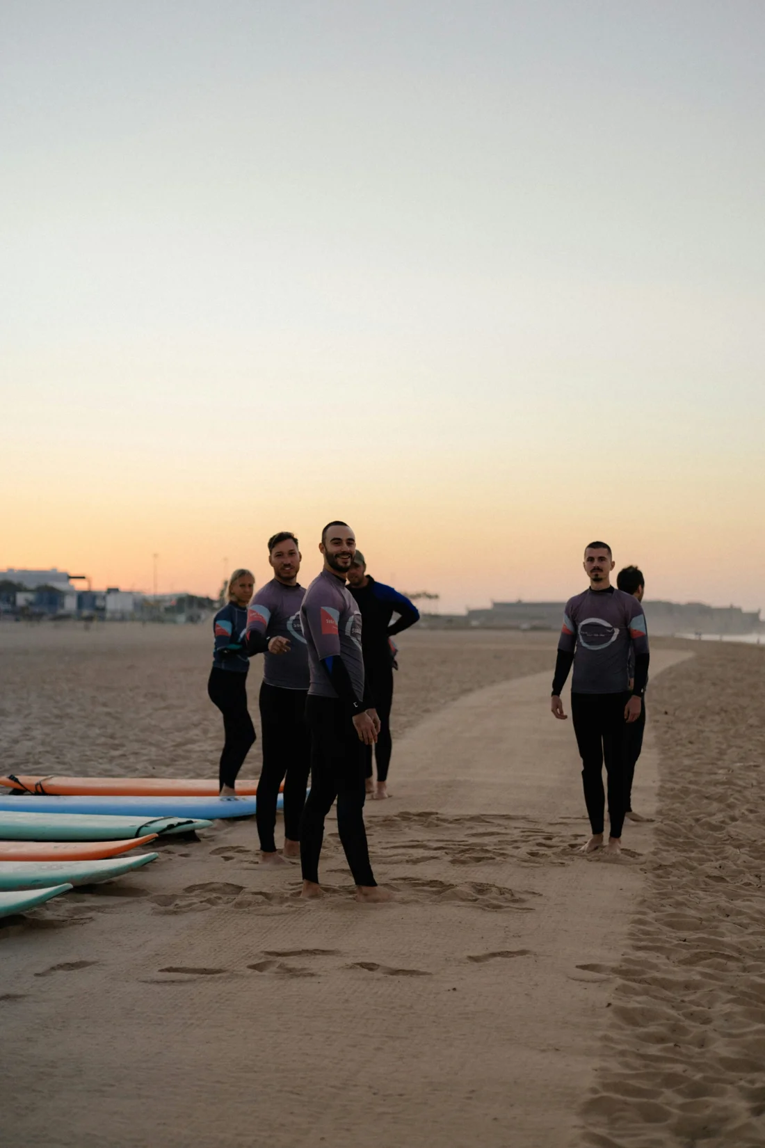 Un groupe en combinaison sur la plage, près des planches de surf