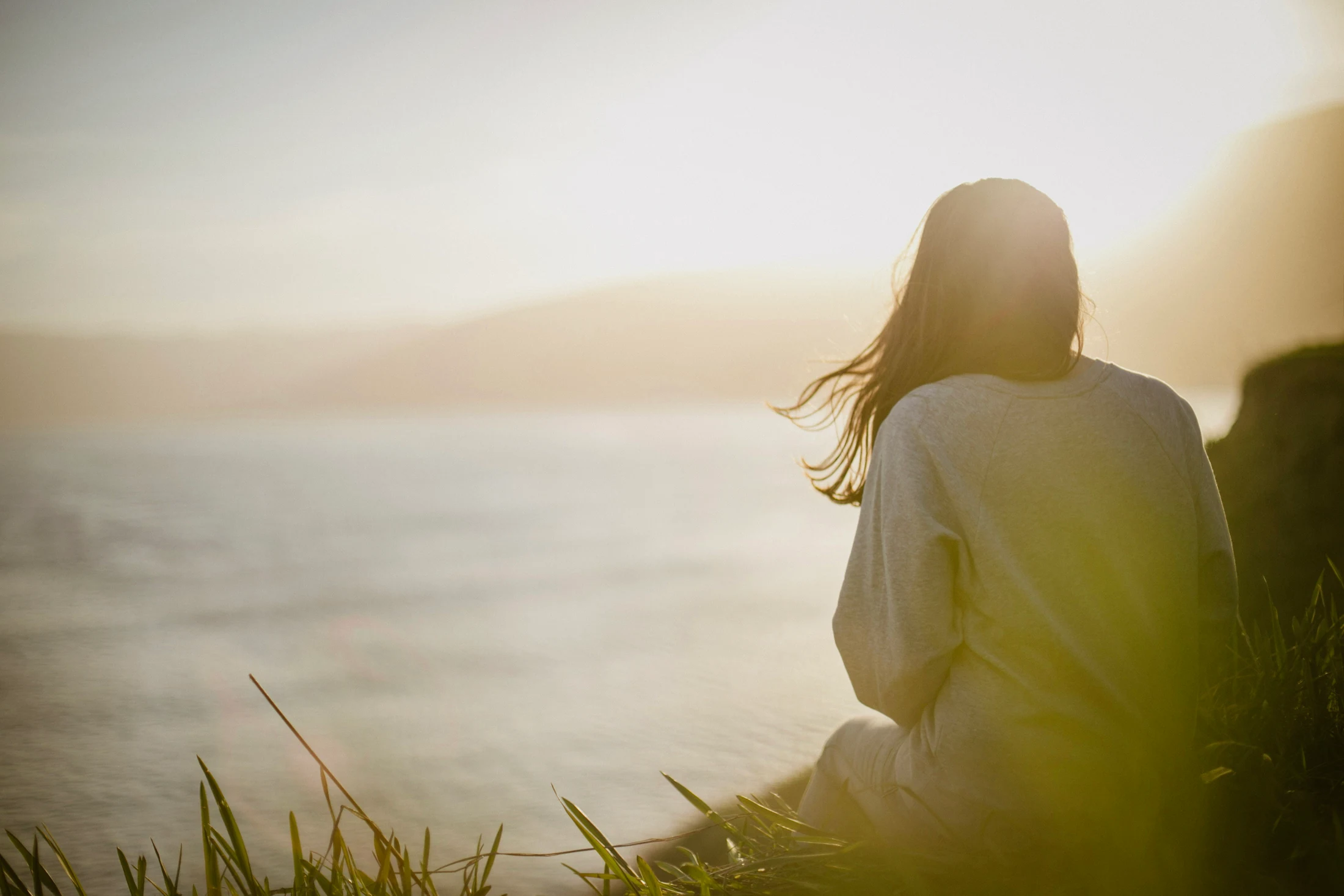 A person takes a moment to reflect by the sea