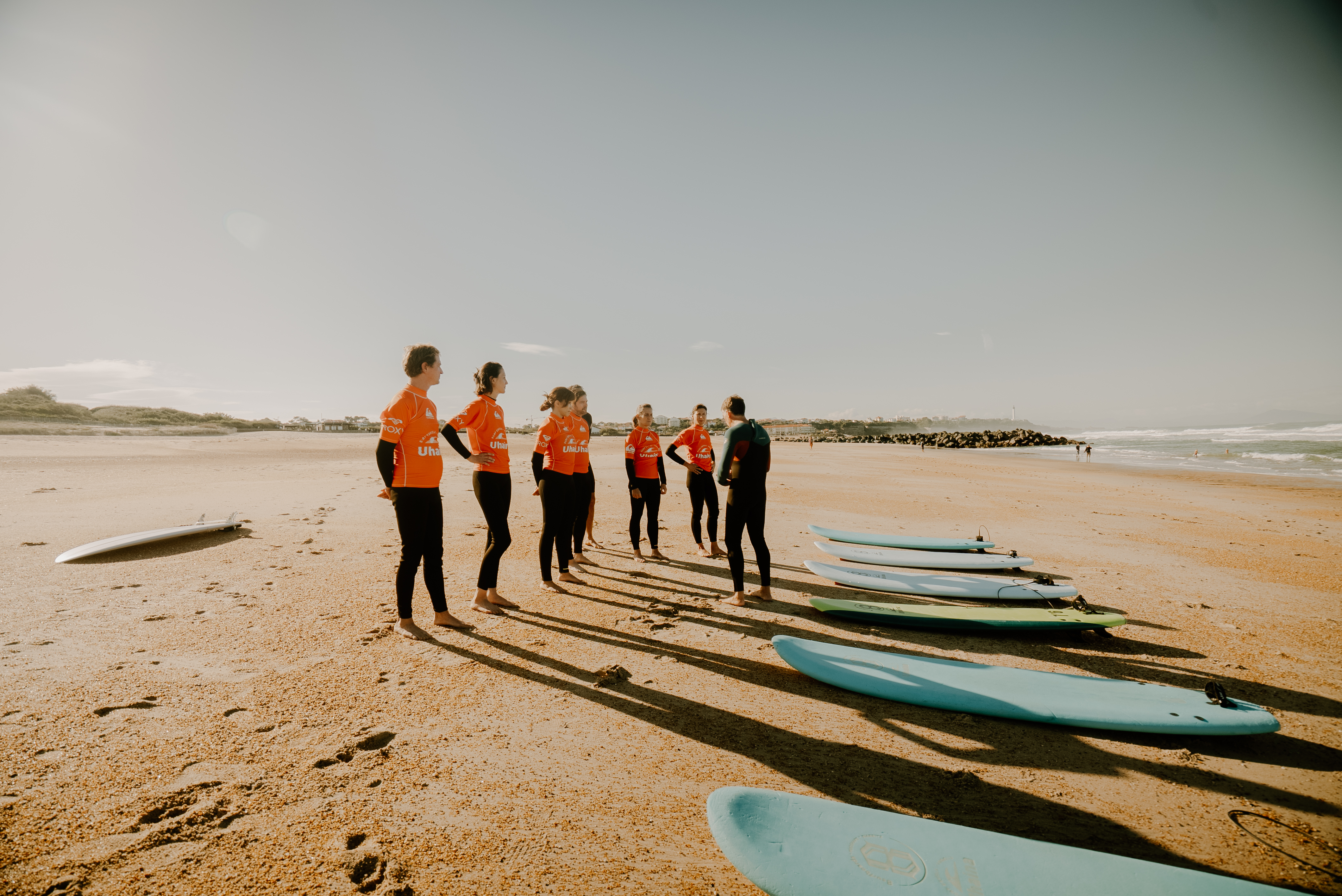 Un groupe en combinaison sur la plage, près des planches de surf